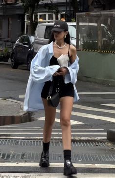 Woman in black shorts and a light blue shirt walking on a street