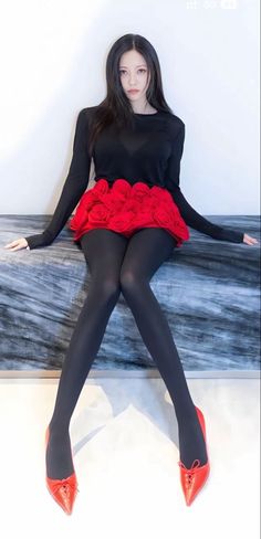Woman with long black hair wearing a red rose skirt and black tights