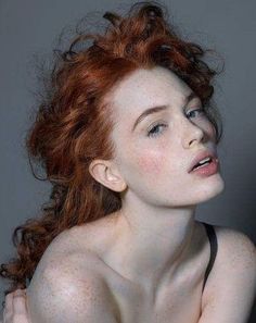 Woman with red curly hair and freckles, looking up with an open mouth