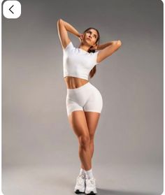 Woman in white athletic wear posing with hands behind her head