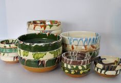 Stacked ceramic bowls with colorful, drippy glaze on a white background