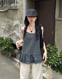 Person in a plaid top and black hat with a heart necklace outdoors