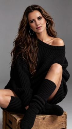 Woman with long hair wearing a black off-shoulder sweater and leg warmers