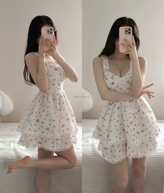 Woman in a white floral dress posing in a bedroom