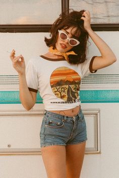 Woman in denim shorts and a crop top with sunglasses and a bandana