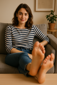 Woman in a striped shirt and jeans sitting on a couch with bare feet