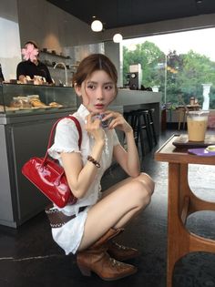 Woman in a white shirt and cowboy boots squatting in a cafe