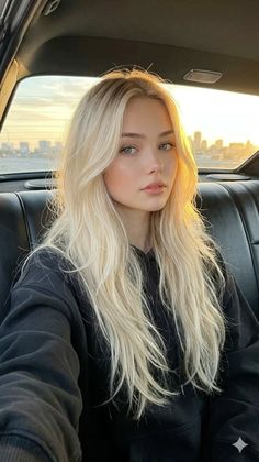 Blonde woman in a black hoodie sitting in a car at golden hour