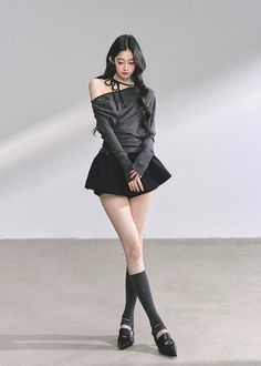 Woman with long black hair wearing an off-shoulder top and mini skirt indoors