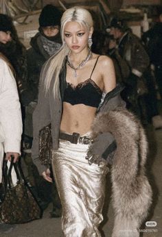 Woman with long blonde hair in a black bralette and metallic pants