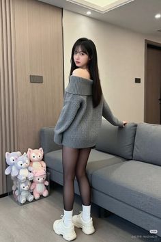 Woman in an off-shoulder sweater and black tights standing indoors