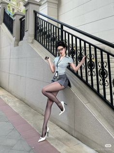 Woman in a short skirt and black pantyhose posing on outdoor stairs