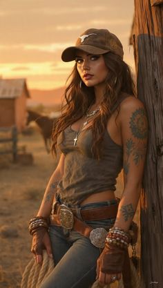 Cowgirl in a baseball cap and jeans leaning against a wooden post at sunset