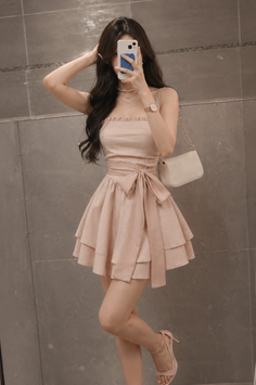 Woman in a pink dress taking a mirror selfie indoors
