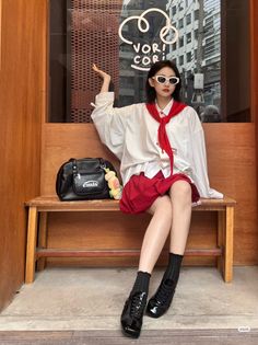 Woman in a white shirt and red skirt sitting on a wooden bench outdoors
