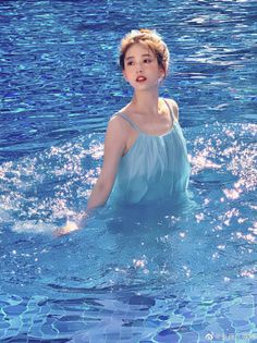 Woman in a light blue dress standing in a sparkling swimming pool