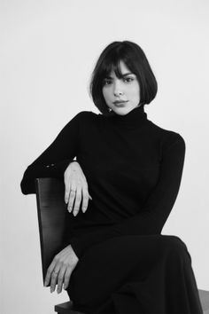 Woman with short hair wearing a black turtleneck, sitting in a studio