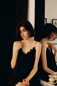 Woman in a black lace-trim camisole with her reflection in a mirror