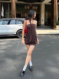 Woman in a brown dress and red bag standing outdoors