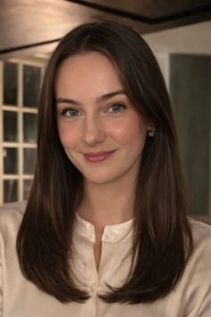 Woman with long brown hair and green eyes wearing a white shirt
