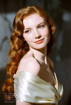 Woman with long red wavy hair in an off-shoulder dress with soft lighting