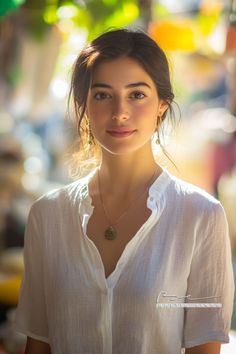 Woman in a white linen shirt with a necklace and earrings outdoors