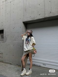 Woman in an oversized t-shirt and slit skirt with a beanie in an urban setting