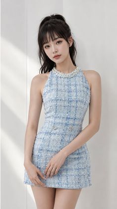 Woman in a blue plaid mini dress with a pearl necklace and ponytail