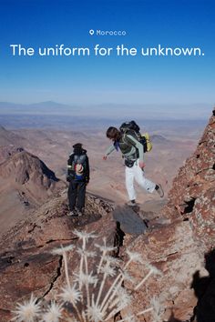 Two people backpacking on a rocky mountain ridge under a clear blue sky