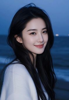Woman with long black hair in a white sweater at night on a beach