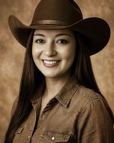 Woman in a cowboy hat and denim shirt smiling in a studio shot