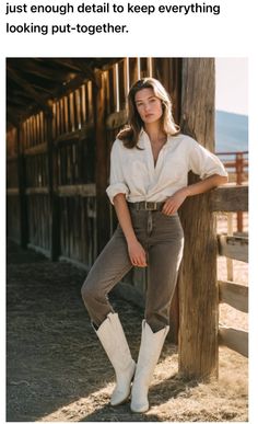 Woman in a white shirt, jeans, and cowboy boots leaning against a wooden fence