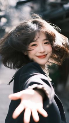 Smiling woman with short hair reaching out, with motion blur in her hair