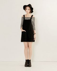 Woman in a black hat and overalls dress with a striped shirt