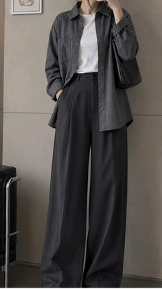 Person in a dark grey oversized shirt and wide leg pants with a white t-shirt
