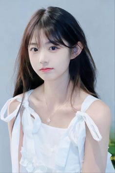 Young woman with long dark hair wearing a white dress and a delicate necklace