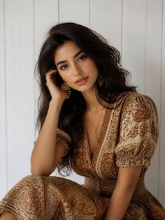 Woman with long dark hair wearing a patterned dress with a deep V-neck