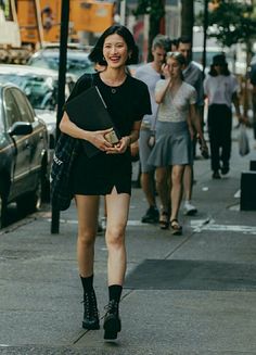 Woman with short black hair smiling and walking on a city street