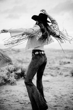 Woman in a cowboy hat and fringe jacket dancing in the desert