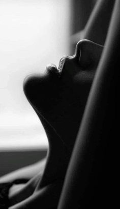Close up of a person's face and neck in dramatic black and white lighting