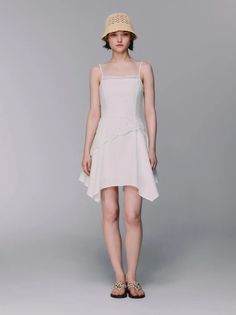 Woman in a white dress and straw hat posing in a studio
