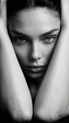 Close up black and white portrait of a woman with her arms framing her face