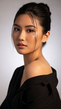 Woman with an updo and black top exposing one shoulder in a studio shot