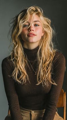 Woman with blonde hair and blue eyes wearing a brown turtleneck