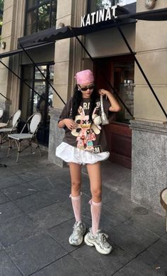 Woman in a pink bandana and oversized t-shirt with white shorts and chunky sneakers