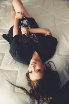 Woman with long hair lying on a bed in a black t-shirt