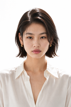 Woman with short dark hair wearing a white shirt and gold earrings
