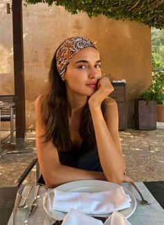 Woman with a patterned headband sitting at an outdoor dining table