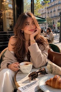 Woman with long hair at an outdoor cafe with coffee and a croissant