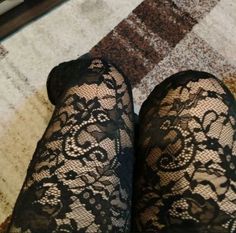 Close up of legs wearing black lace stockings on a patterned carpet